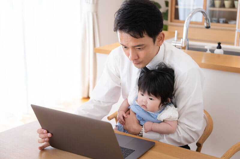 子どもを抱えながら仕事するお父さん